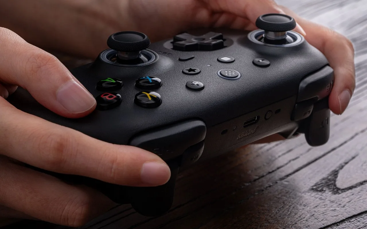 Two hands holding the black 8BitDo Ultimate 2 controller