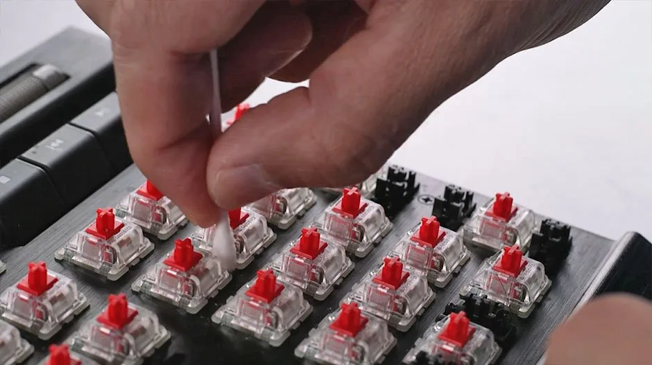 Cotton swab cleaning the gap between two mechanical keyboard switches