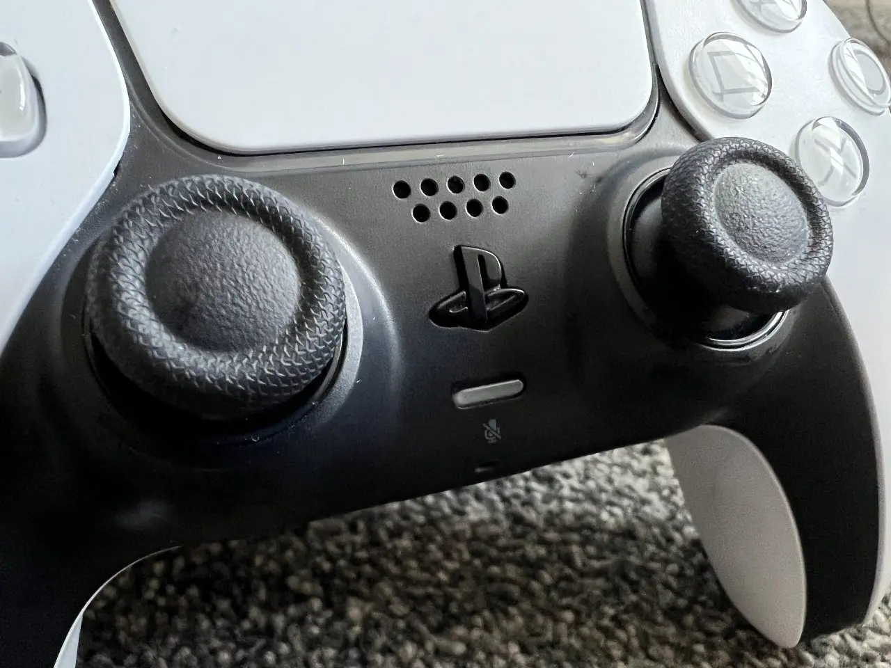 PS button in the center of a DualSense controller between the analog sticks