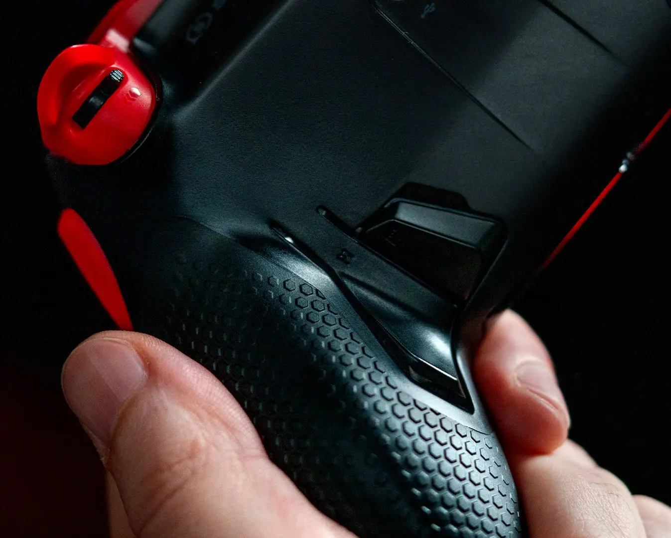 Hand gripping a Scuf Envision Pro with a rear paddle visible beside the textured grip