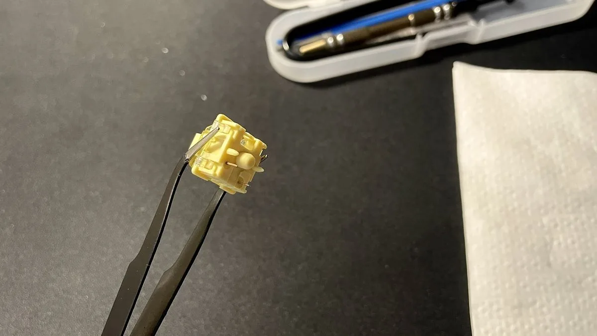 Mechanical keyboard switch held with tweezers for the O-ring mod