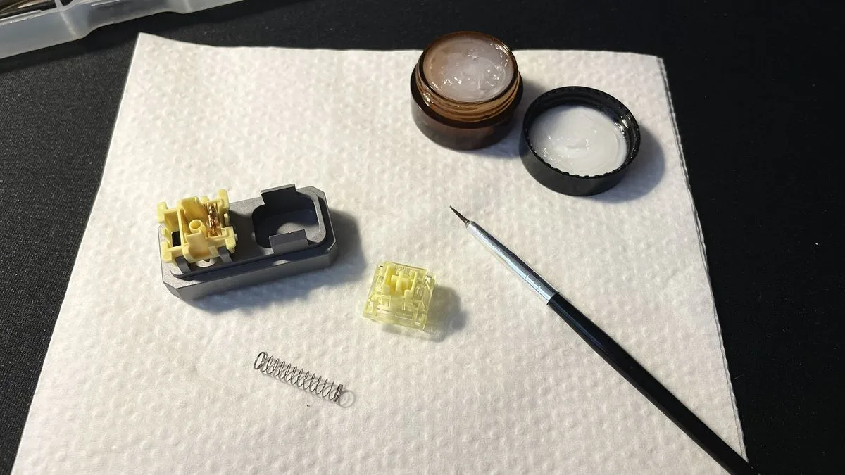 Opened mechanical switch in a switch opener next to a lube jar and brush