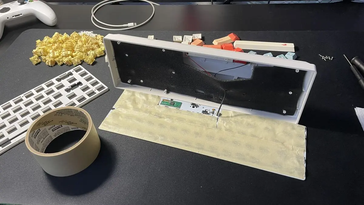 Masking tape applied to the back of a keyboard PCB with a gap for the battery wire