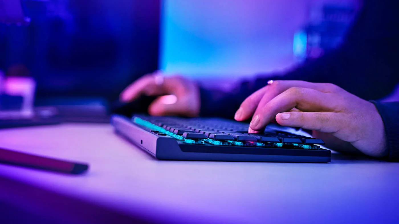 Side view of hands typing on the Logitech G515 Lightspeed TKL with backlit low-profile keys