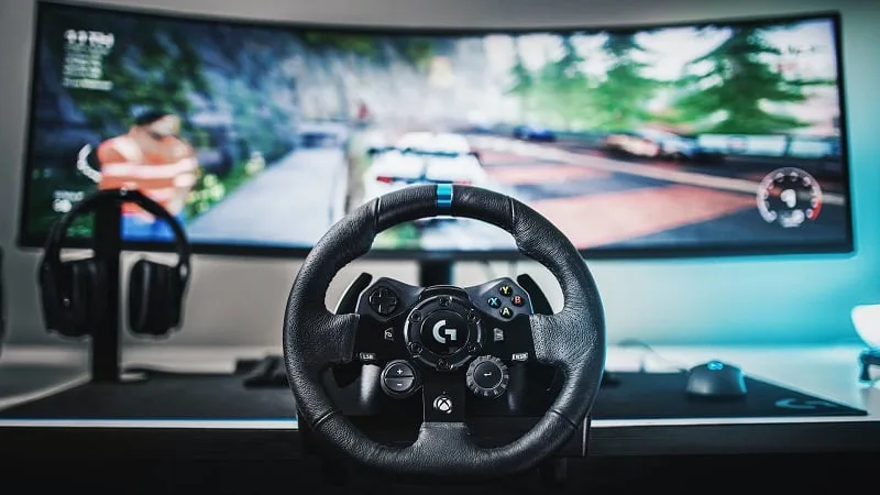 Logitech G923 Xbox and PC racing wheel clamped to a desk in front of a curved monitor showing a racing game