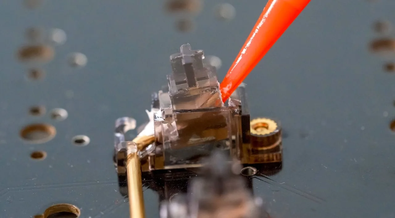 Applying lube to a keyboard stabilizer housing on the PCB