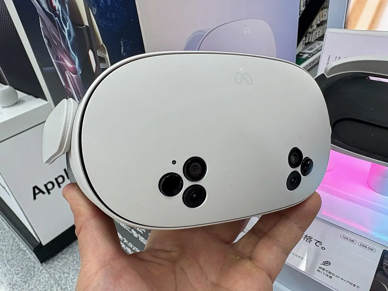 Front of a Meta Quest 3S headset held in a hand, showing its two triangular camera clusters