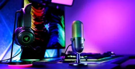 Razer Seiren V3 Chroma with glowing RGB grille on a gaming desk next to a Razer headset