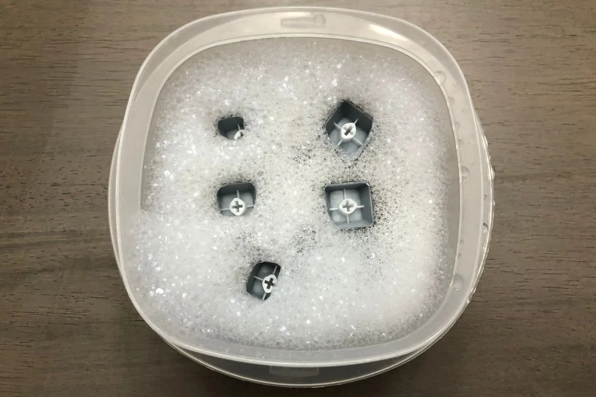 Keycaps soaking in a bowl of warm soapy water