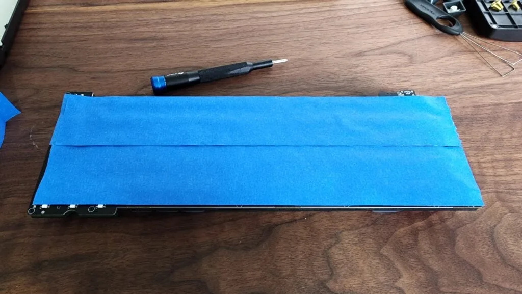 Keyboard PCB covered with additional layers of painter's tape for the tape mod