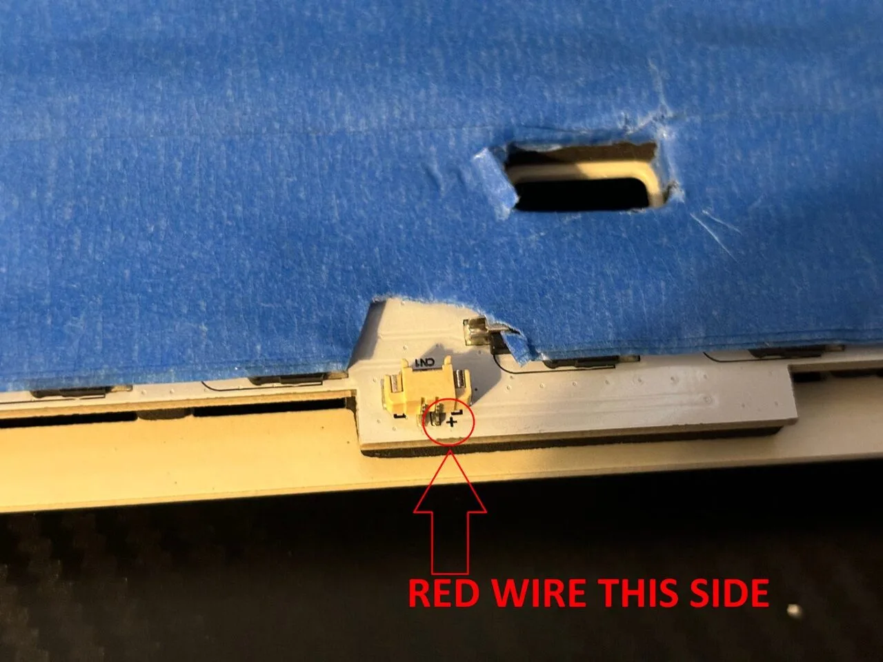 Battery connector on a taped keyboard PCB with the plus side marked for the red wire