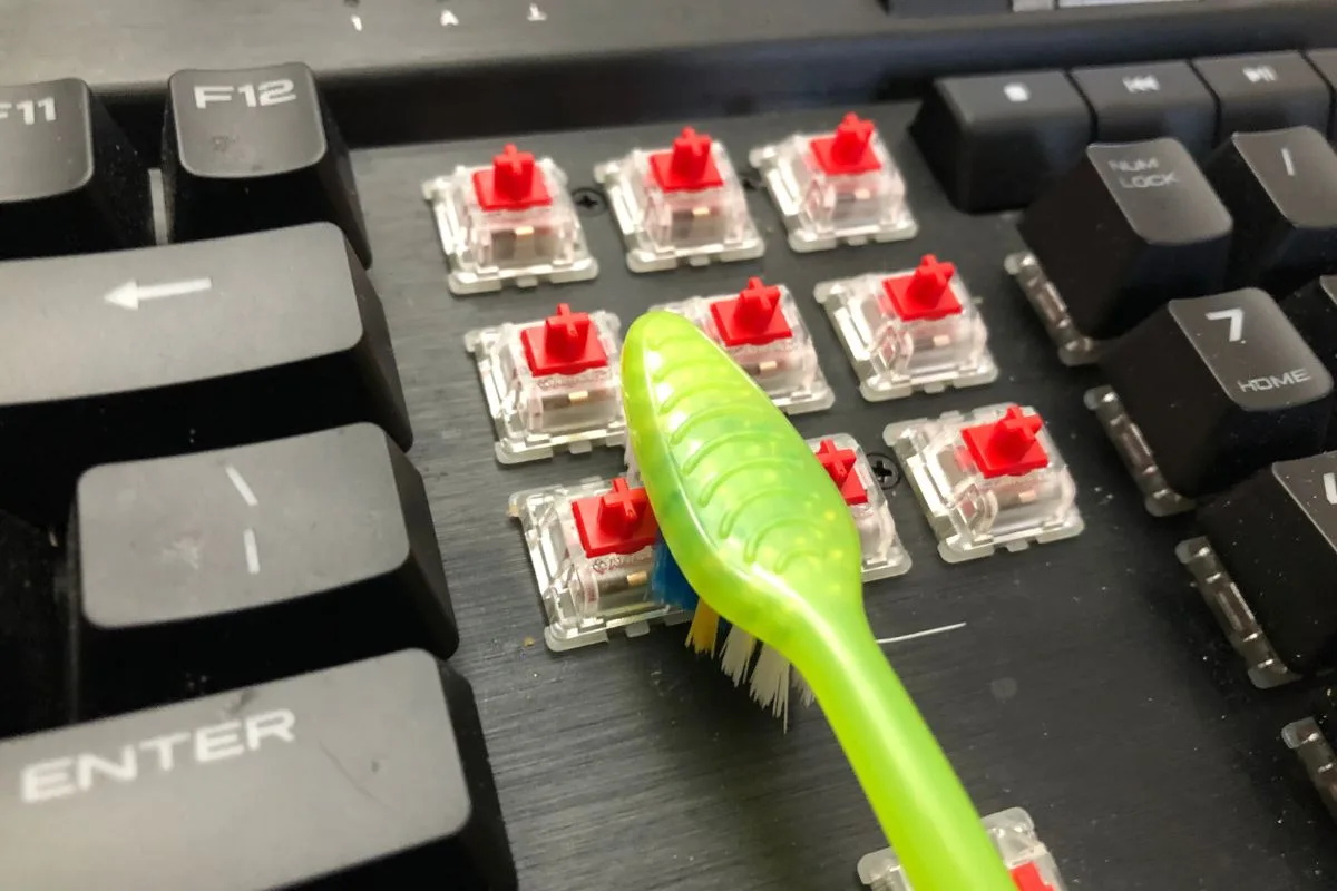 Soft toothbrush scrubbing debris from around mechanical keyboard switches