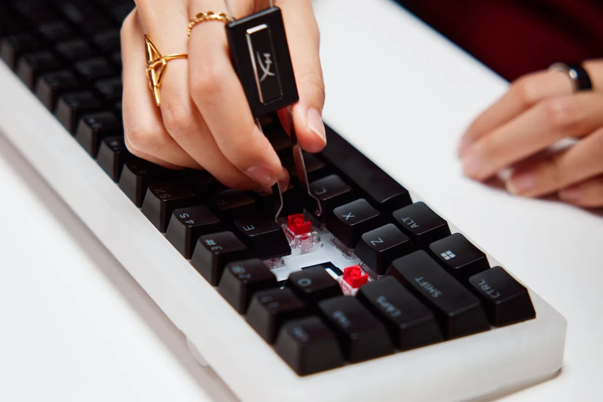 Hand using a keycap puller to lift a keycap off a mechanical keyboard