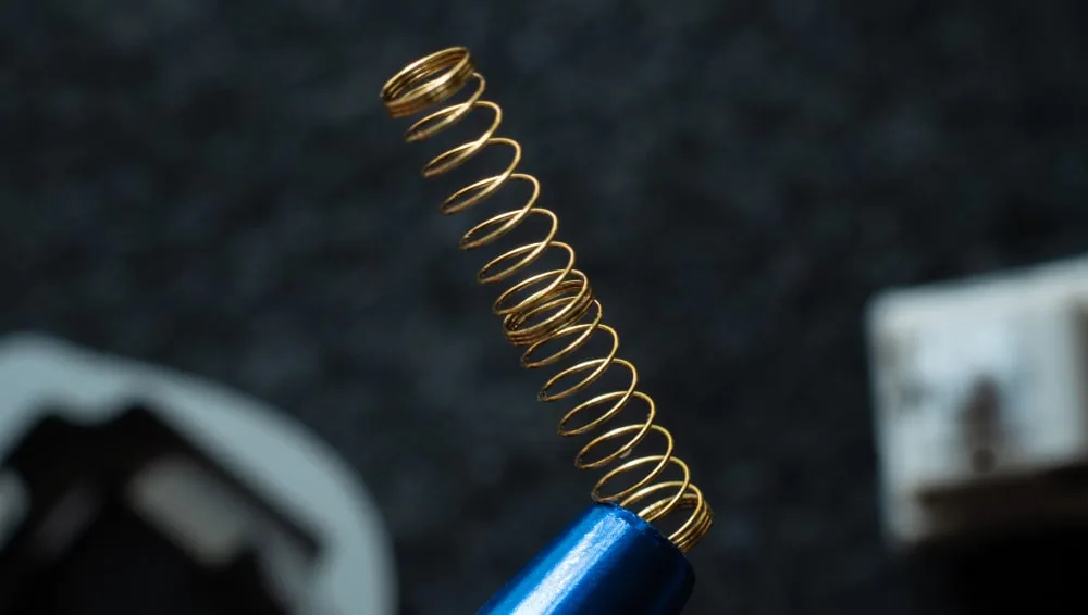 Gold switch spring held up on a brush handle after lubing