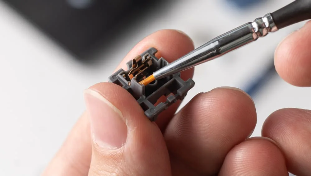 Brush applying lube to the bottom housing of a mechanical keyboard switch