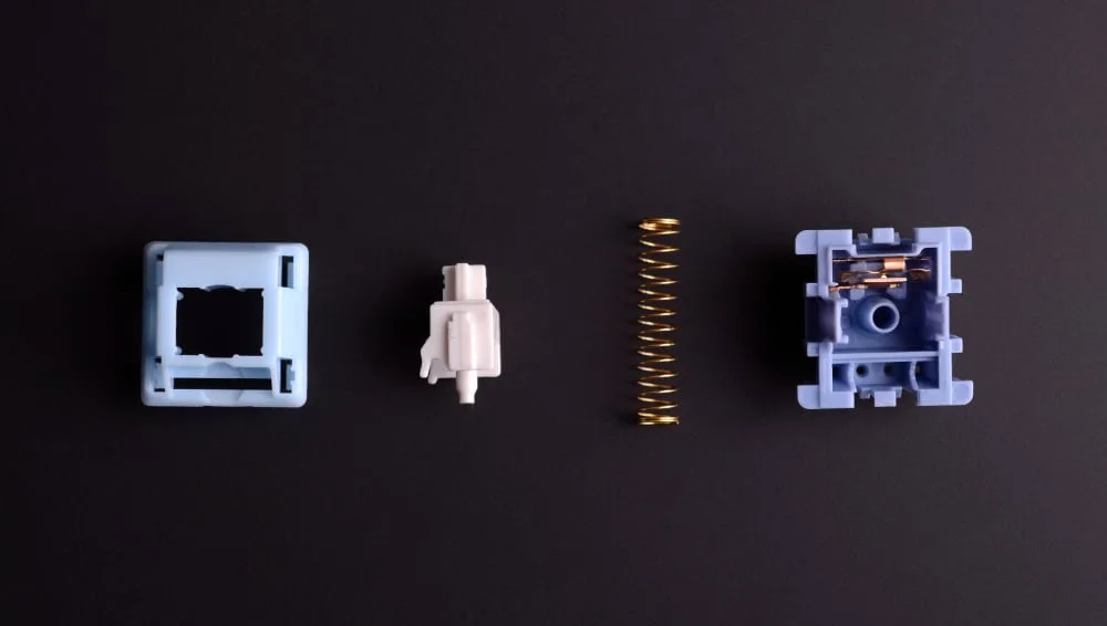 Mechanical keyboard switch taken apart into top housing, stem, spring and bottom housing