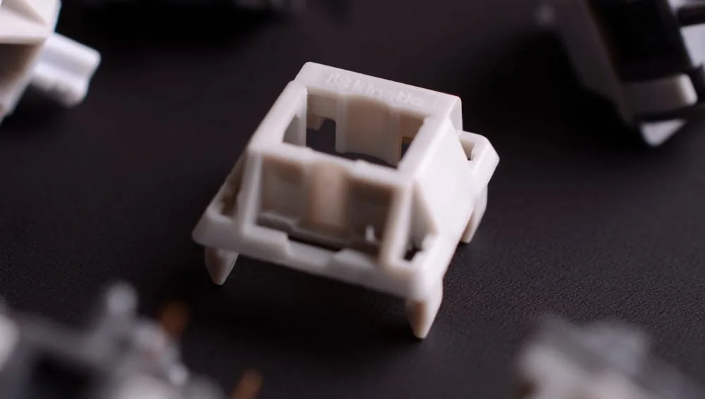 White mechanical switch top housing on a dark surface before lubing