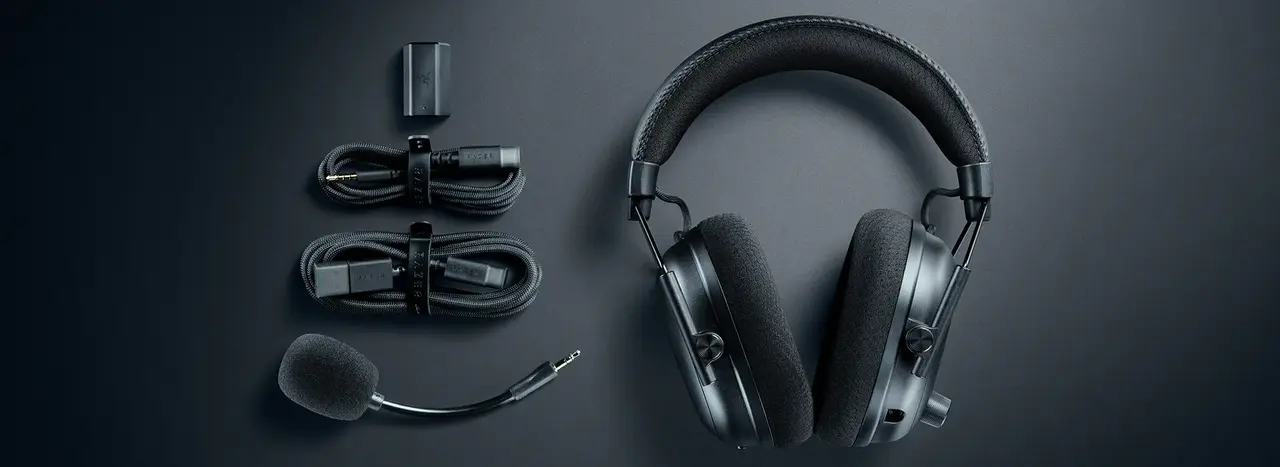 Razer BlackShark V3 Pro headset laid flat beside its USB dongle, cables and detachable boom microphone