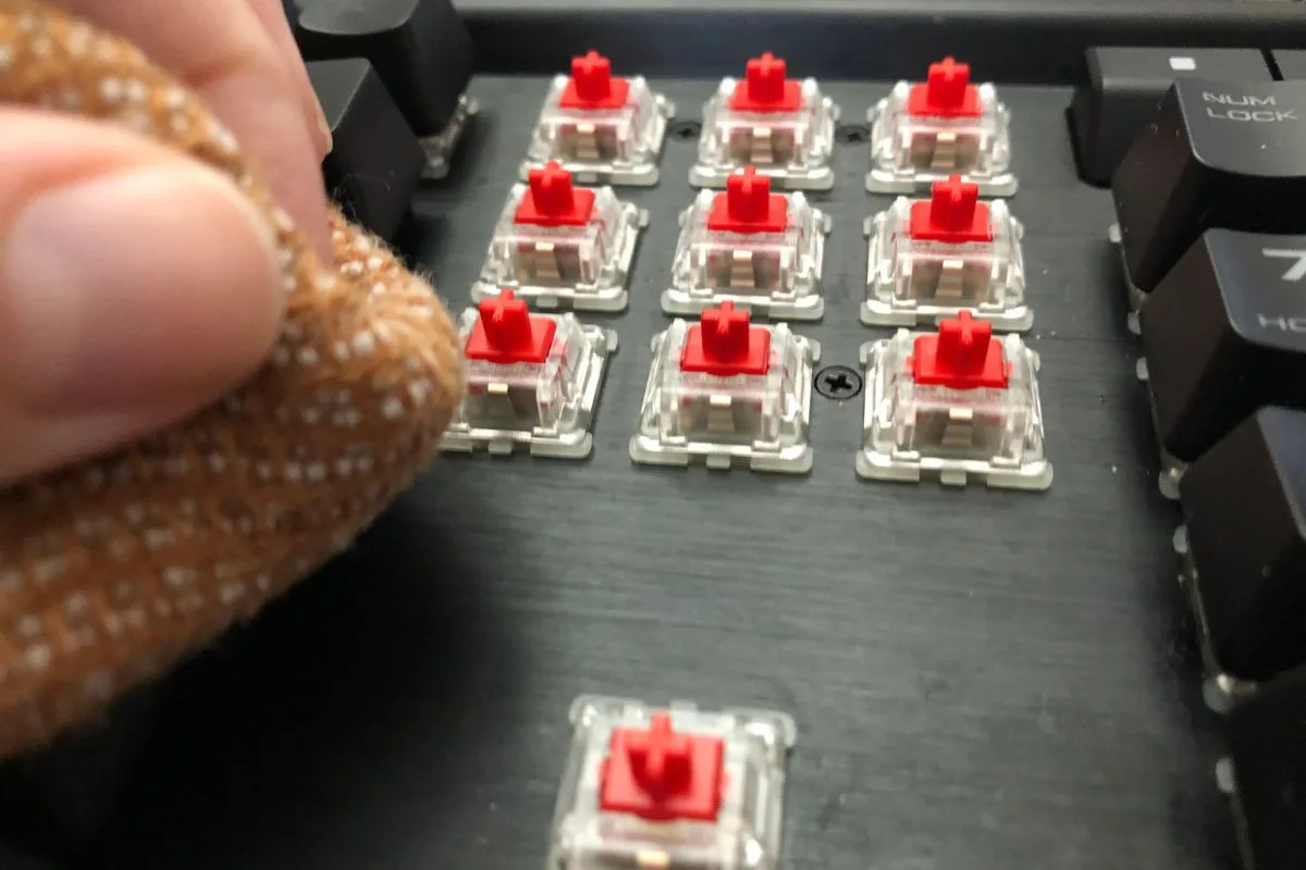 Damp cloth wiping the plate between exposed mechanical keyboard switches