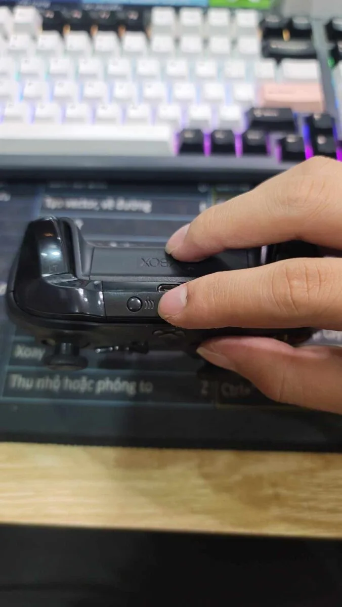 Finger holding the small Pair button on the top edge of an Xbox controller